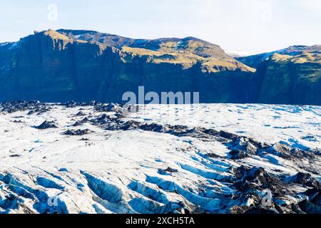 Une chaîne de montagnes moussues avec un glacier au premier plan. Glacier Solheimajokull, Islande. Les montagnes sont couvertes de mousse et le glacier fond Banque D'Images