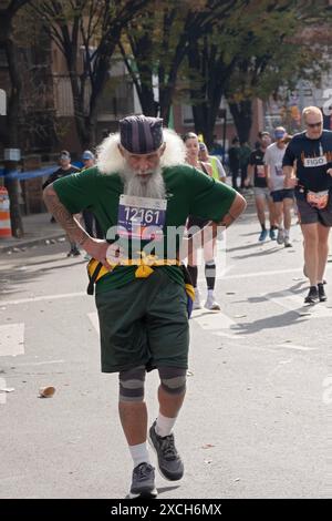 Un coureur plus âgé avec de gros cheveux et une barbe grise semble battu après seulement 10 miles du marathon de New York. À Williamsburg, Brooklyn, New York. Banque D'Images