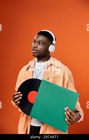 Homme afro-américain élégant avec des écouteurs tenant un disque vinyle. Banque D'Images