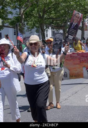 Un membre du Peekskill Seniors Club marche lors de la parade de la quinzième année avec un drapeau et une photo du président Obama. Dans Peekskill, juin 2024. Banque D'Images