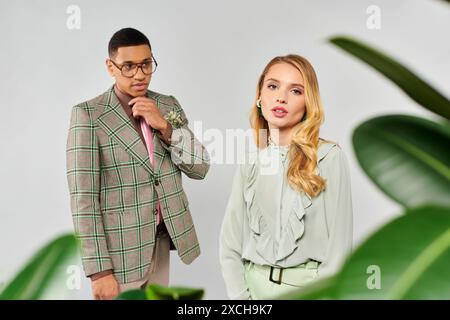 Un homme et une femme élégamment debout à côté d'une plante, admirant sa beauté. Banque D'Images