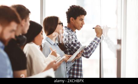 Les étudiants qui écrivent des équations d'algèbre sur tableau blanc en classe Banque D'Images