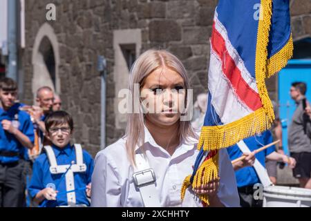 Jeune blonde porte-drapeau féminin avec bande de flûte loyaliste. Portrush, le 1er juin 2024, défilé Junior Orange Order à travers la ville côtière. Banque D'Images