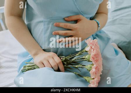 Femme enceinte touchant son ventre avec amour et tenant un beau bouquet de fleurs Banque D'Images