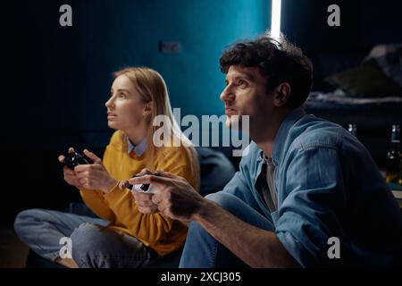 Femme et homme jouant à un jeu vidéo en utilisant des joysticks ensemble Banque D'Images