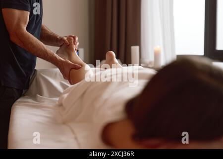 Femme cliente souffrant de crampes appréciant la thérapie de massage sportif des jambes Banque D'Images