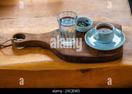 Présentation de café turc avec du chocolat aux galets et un verre d'eau, mettant en valeur une configuration traditionnelle et élégante sur la table. Banque D'Images