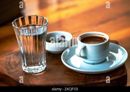 Présentation de café turc avec du chocolat aux galets et un verre d'eau, mettant en valeur une configuration traditionnelle et élégante sur la table. Banque D'Images