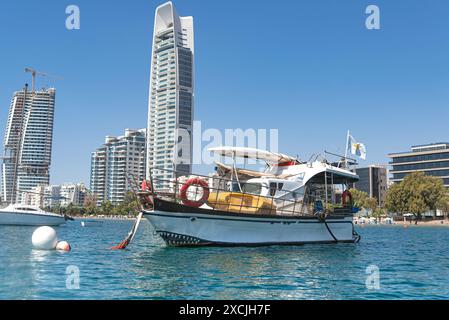 Bateau à passagers blanc amarré sur la rive de Limassol avec des gratte-ciel modernes en arrière-plan par jour ensoleillé. Chypre Banque D'Images