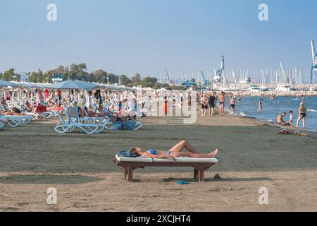 Larnaca, Chypre - 07 septembre 2019 : une femme prend un bain de soleil sur un banc en bois sur une plage de Finikoudes Banque D'Images