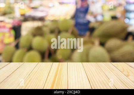 Table en bois et supermarché avec des fruits de durian sur les étagères fond flou avec bokeh Banque D'Images