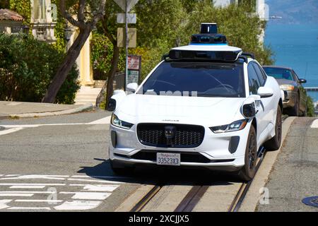 San Francisco, Californie, États-Unis d'Amérique - 14 juin 2024 : un véhicule autonome de Waymo, leader dans le développement de voitures autonomes, conduit de manière autonome dans une rue animée de San Francisco, Californie *** Ein autonomes Fahrzeug von Waymo, einem führenden Unternehmen in der Entwicklung von selbstfahrenden Autos, fährt autonom in einer belebten Straße à San Francisco, Kalifornien Banque D'Images