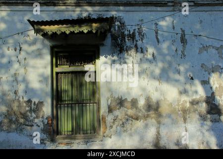 Cadres de fenêtres en bois classiques avec des murs vieillis, dans un faisceau de lumière chaud. Banque D'Images