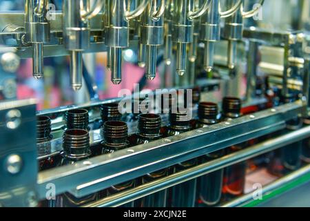 Bouteilles en verre dans une bande transporteuse sur une remplisseuse verticale automatique de haute qualité. Dans la chaîne de production d'usine Banque D'Images