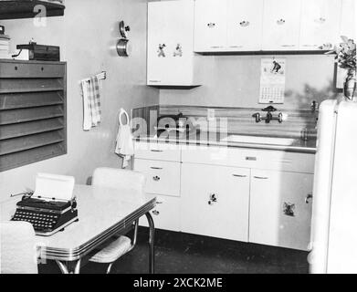 Intérieur de la maison avec cuisine, réfrigérateur, évier et table de cuisine avec une machine à écrire prise en Amérique des années 1950 Banque D'Images