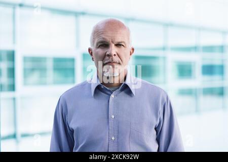 Homme d'affaires mature semble contemplatif dans un hall de bureau moderne, réfléchissant sur l'éthique des affaires et l'impact technologique futur Banque D'Images