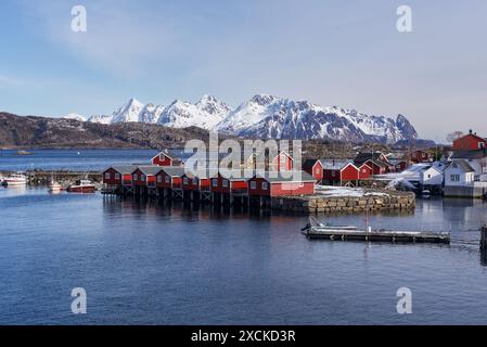 Svolvaer, îles Lofoten, Norvège 03.28.2024 vue sur les cabanes de pêcheurs rorbuer rouges traditionnelles avec des montagnes enneigées en arrière-plan. Banque D'Images