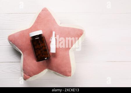 Oreiller, pilules et spray nasal sur fond de bois blanc, vue de dessus. Espace pour le texte Banque D'Images