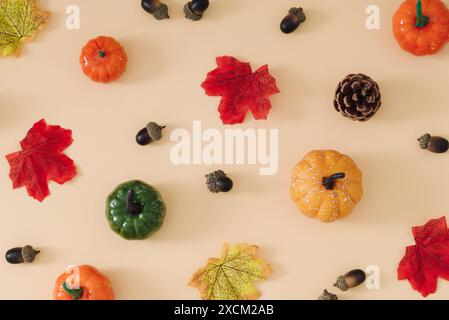 Modèle créatif d'automne ou d'automne fait avec des feuilles tombées colorées, des citrouilles, des pommes de pin et des noix sur fond beige. Concept d'automne rétro minimal. Banque D'Images