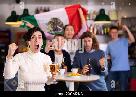 Joyeux fans de l'équipe mexicaine célébrant la victoire au bar de nuit Banque D'Images