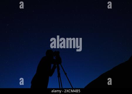 Photographe prenant des photos du ciel nocturne. Silhouette de l'homme sur fond de ciel étoilé nocturne. Étoiles Banque D'Images