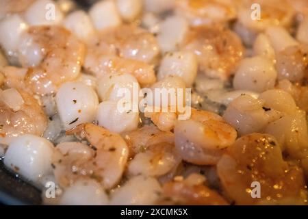 Cuisson des crevettes et des coquilles Saint-Jacques avec du beurre d'ail Banque D'Images