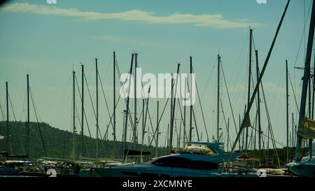 Un grand nombre de bateaux sont amarrés à une marina. Les bateaux sont de différentes tailles et formes, et ils sont tous alignés dans une rangée. La scène est paisible a Banque D'Images