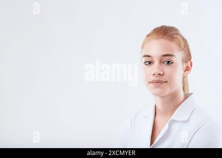 Portrait d'une jeune femme médecin portant un manteau blanc, posant devant un fond blanc, avec une expression neutre Banque D'Images