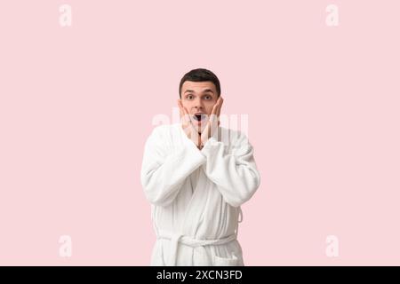 Portrait de jeune homme choqué en peignoir sur fond rose Banque D'Images