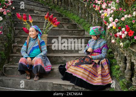 Fleurs des femmes hmong assises sur les escaliers du palais des rois Hmong (Vau Meo) à bac Ha, province de Lao Cai, Vietnam Banque D'Images