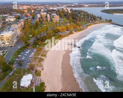 Vue aérienne sur une longue plage de sable sous les bâtiments d'une ville côtière sous le soleil tôt le matin à Port Macquarie en Nouvelle-Galles du Sud Banque D'Images
