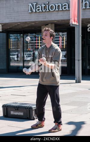 Domenyk la Terra jongle avec des balles devant le National Theatre, sur le Queen’s Walk, Southbank, Londres. Banque D'Images