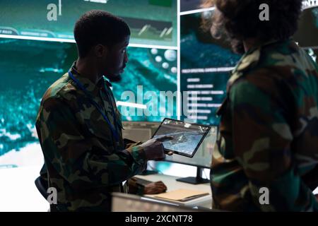 Personnel militaire recueillant des données à partir d'images de surveillance par satellite, examinant des informations pour une mission d'unité d'infanterie dans la salle de surveillance. Ingénieurs INFORMATIQUES exploitant des équipements de haute technologie, agence fédérale. Banque D'Images