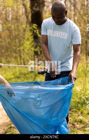 Des bénévoles ramassent les ordures et les bouteilles en plastique dans la forêt, protègent l'habitat naturel et font du bénévolat. Les activistes nettoient les bois en équipe, recyclent les déchets. Banque D'Images