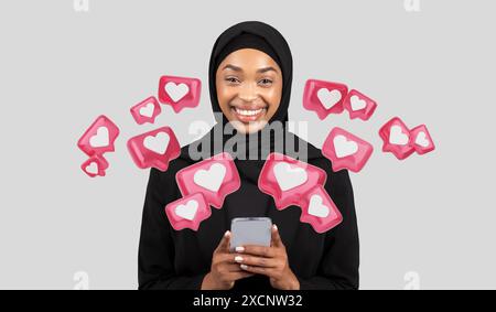 Heureuse jeune femme afro-américaine en hijab discutant au téléphone Banque D'Images