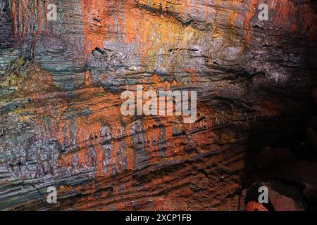 Roches volcaniques en fer rouge, orange et brun, vue rapprochée. Mur du tunnel de lave (Raufarholshellir), Islande. Banque D'Images