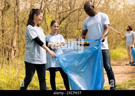 Groupe d'écologistes travaillant à nettoyer la forêt de la jonque, ramassant les ordures et les déchets plastiques dans des sacs. De jeunes activistes qui s’emparent des ordures et du recyclage, soutiennent la justice écologique. Banque D'Images