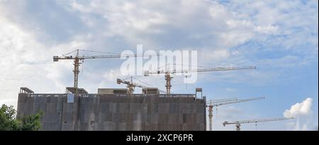 travail de grue à tour de construction avec ouvrier de construction sur le dessus du bâtiment, utilisé dans le chantier de construction avec ciel bleu. Banque D'Images