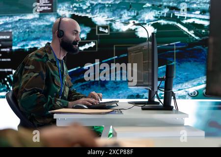 Technicien INFORMATIQUE qualifié surveillant les images radar de surveillance enregistrées sur pc et grand écran dans le centre de commandement fédéral. Personnel militaire travaillant dans la division de reconnaissance du gouvernement. Banque D'Images