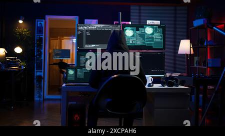 Hacker arrivant dans la base secrète avec ordinateur portable, prêt à commencer à programmer des virus. Arnaqueur dans la tanière criminelle ouvrant le carnet pour exploiter les serveurs de réseau et contourner les mesures de sécurité, caméra B. Banque D'Images