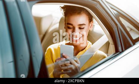 Femme African Americam texto au téléphone dans la voiture Banque D'Images
