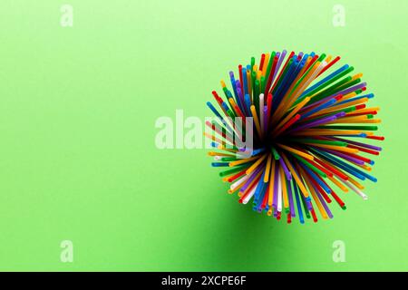 Vue de dessus de nombreux tubes à cocktail en plastique multicolore dans un verre.Pailles à boire de couleurs vives isolées sur fond blanc. Banque D'Images