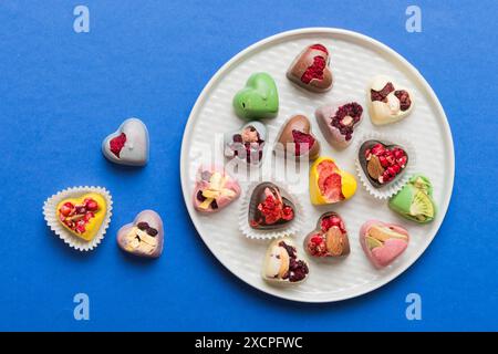 Assiette avec différents chocolats sur fond coloré. Assortiment de chocolats fins vue de dessus vith espace copie concept santé et obésité. Banque D'Images