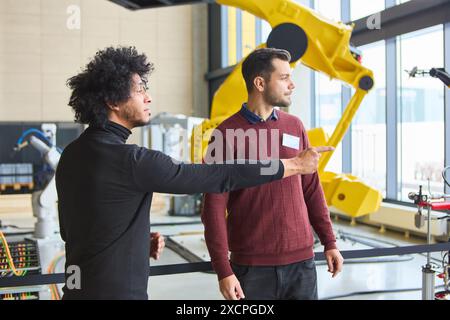 Ingénieurs discutant de la technologie robotique et de la programmation dans un contexte industriel, en se concentrant sur le développement de bras robotiques avancés pour l'automatisation Banque D'Images