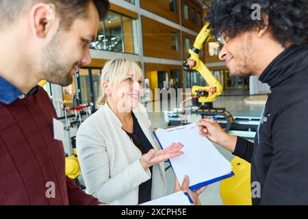 Ingénieurs collaborant au développement robotique dans un environnement industriel. Focus sur les robots à bras de préhension utilisés dans diverses industries telles que automotiv Banque D'Images