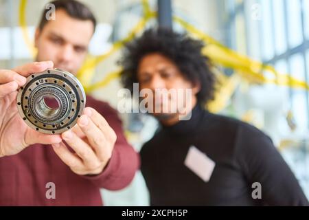 Deux ingénieurs inspectent de près un composant robotique dans un laboratoire technologique, se concentrant sur l'automatisation industrielle et le développement robotique. Banque D'Images