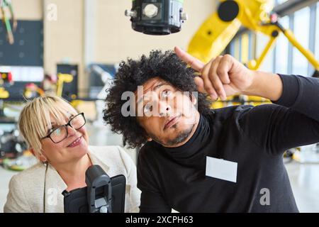 Ingénieurs collaborant sur la programmation et l'automatisation de bras robotisés dans un espace de travail industriel moderne, en se concentrant sur les avancées techniques et innovantes. Banque D'Images