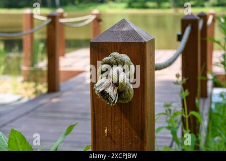Mise au point sélective sur une corde nouée à un poteau en bois sur le quai. Mise au point sur le premier plan, arrière-plan flou. Banque D'Images
