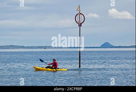 Firth of Forth, Portbello, Édimbourg, Écosse, Royaume-Uni. Un mâle qui pagaie dans un kayak jaune dans le soleil lumineux juste à côté de la plage de Portobello avec une température de 16 degrés centigrades. Credit : Arch White/Alamy Live news. Banque D'Images