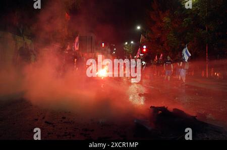 JÉRUSALEM - 17 JUIN : des manifestants antigouvernementaux scandent des slogans alors qu'ils laissent échapper la fumée rouge lors d'une manifestation près de la résidence privée du premier ministre, contre le gouvernement de Netanyahou et appelant à de nouvelles élections le 17 juin 2024 à Jérusalem. Les frustrations des Israéliens envers le gouvernement dirigé par Benjamin Netanyahou ont persisté alors que plus de 100 otages restent captifs à Gaza, après près de huit mois de guerre entre Israël et le Hamas, le groupe militant palestinien qui a attaqué Israël le 7 octobre. Banque D'Images